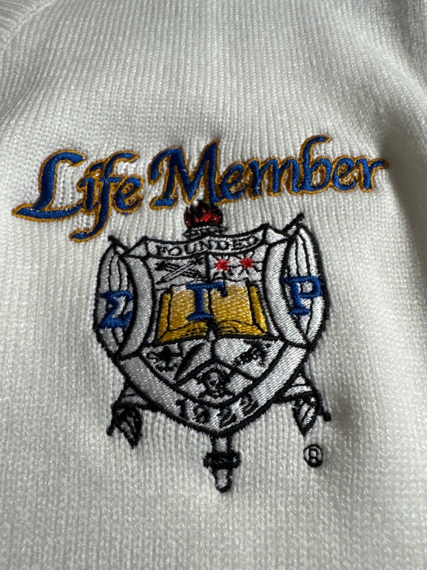 Embroidered logo on a white fabric with 'Life Member' text