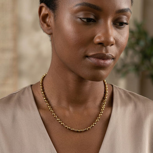 Delicate gold hematite necklace on a woman, highlighting subtle texture and fine links in natural light.