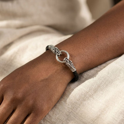 Black twisted leather bracelet with silver lion head accents holding a ring