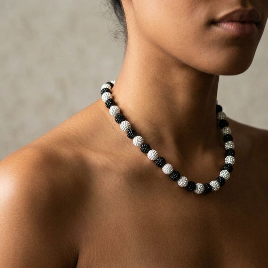 Tiny 12mm white and black clay crystal Shamballa necklace on a minority woman's collar, with natural lighting and neutral background.